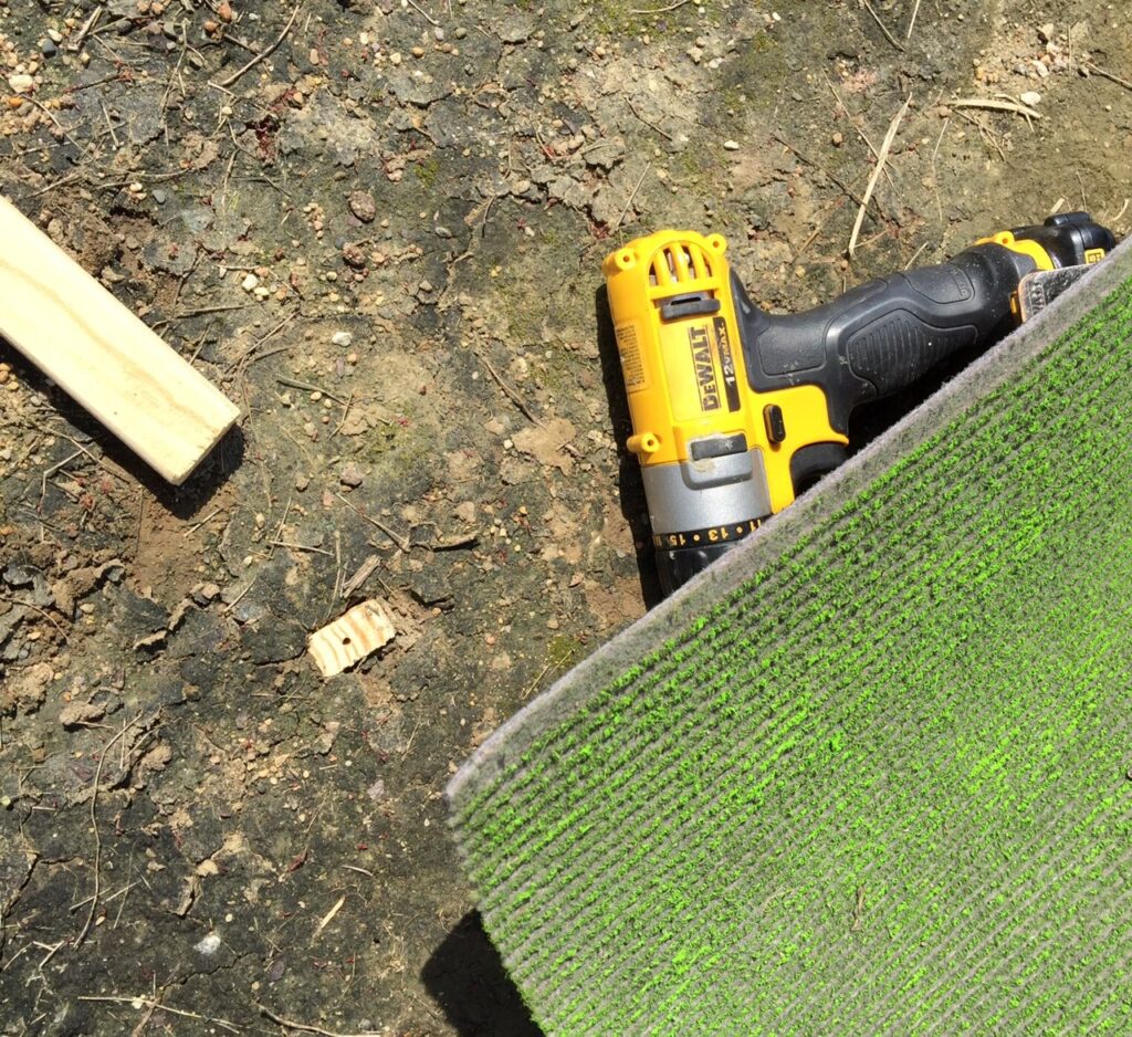 A piece of carpet runner, a drill, and a wooden stake