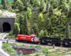 A red-and-black Canadian Pacific diesel switcher pulls a pair of empty hoppers in a wooded setting