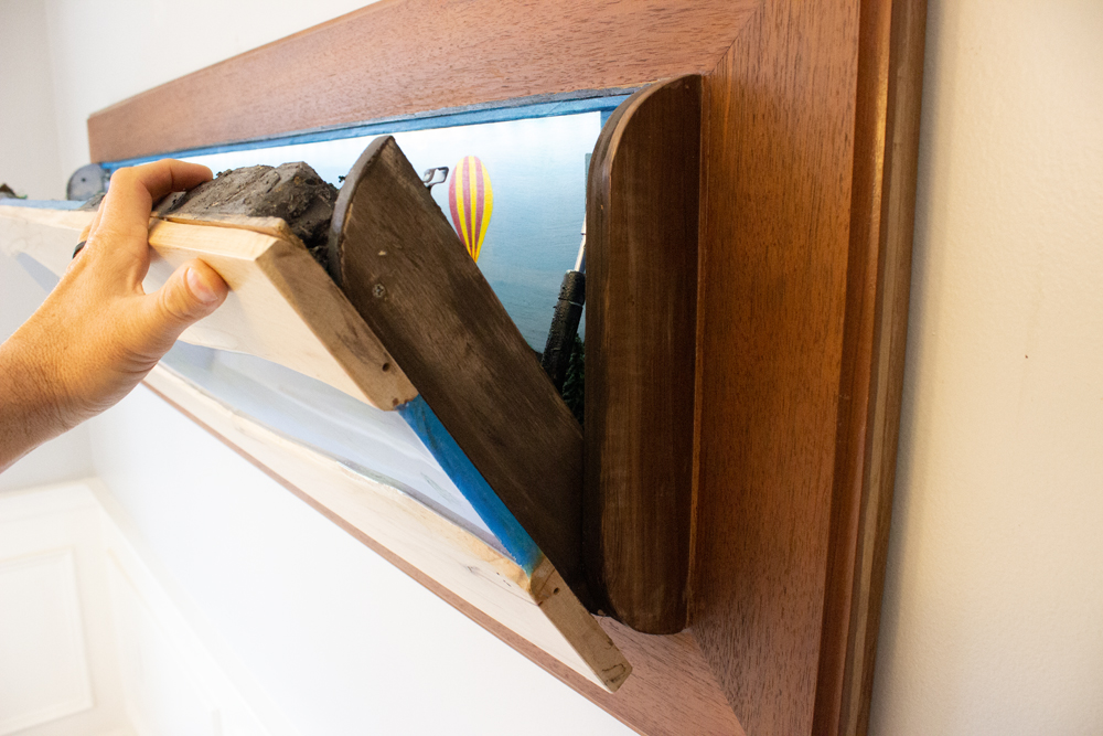 A hand folding shut the layout to conceal it behind the art piece.