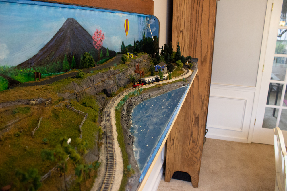 A train pulling two cars passes alongside the ocean coast