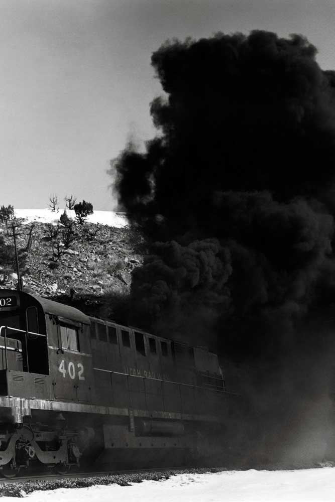 Black smoke follows diesel locomotives exiting tunnel 