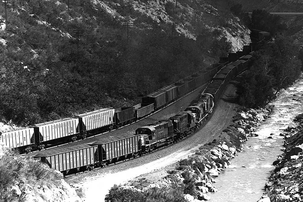 Diesel locomotives with coal train along river in canyon