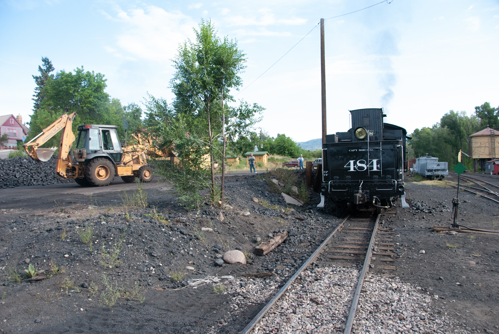 Tractor loads coal into steam locomotive
