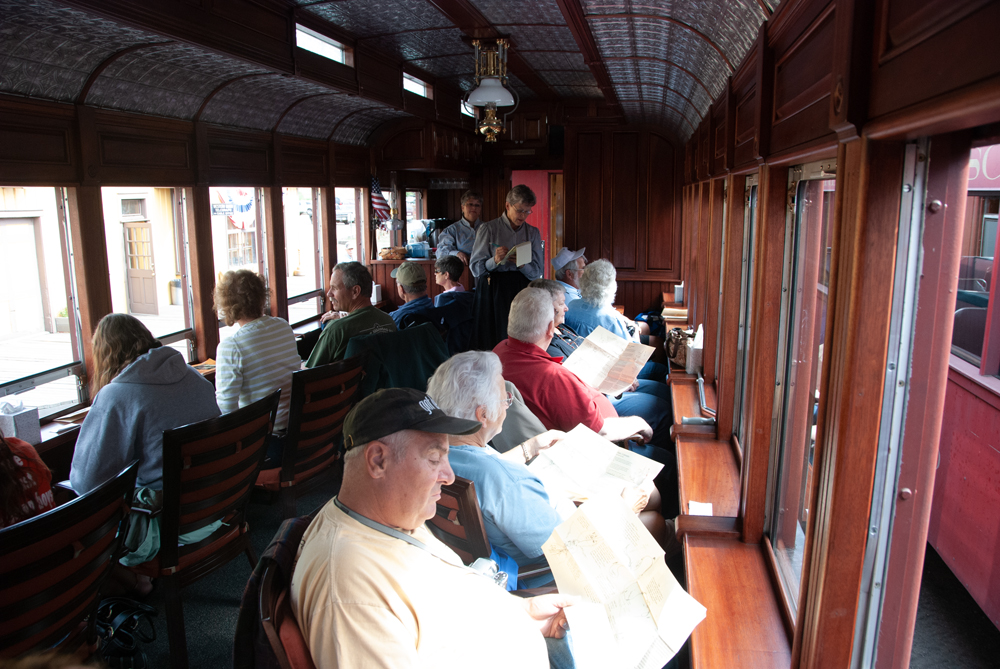 Inside of passenger car, with passengers in seats that face windows