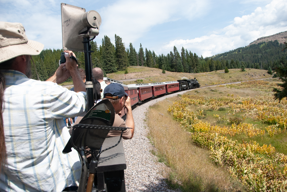 People take pictures in open-air car as train rounds curve