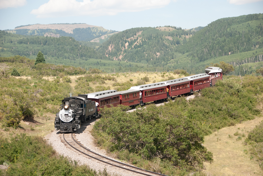Train negotiates curve with mountains as backdrop