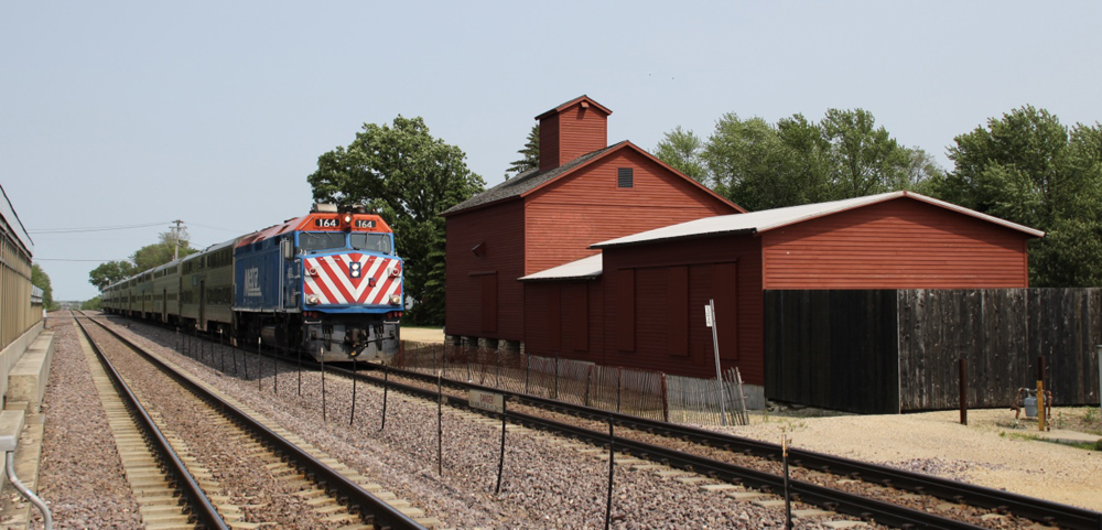 Train passes red wooden barn.