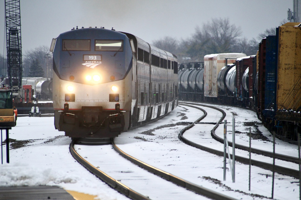 Passenger train passes through S curve on one track as freight train passes in other direction.