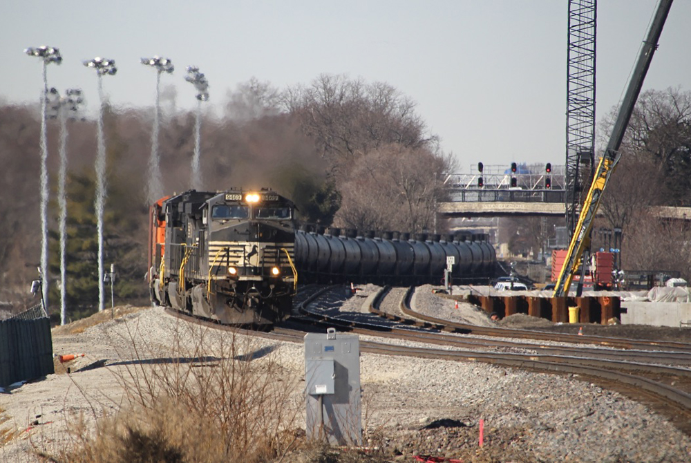 Black diesels lead long string of tank cars through curves.