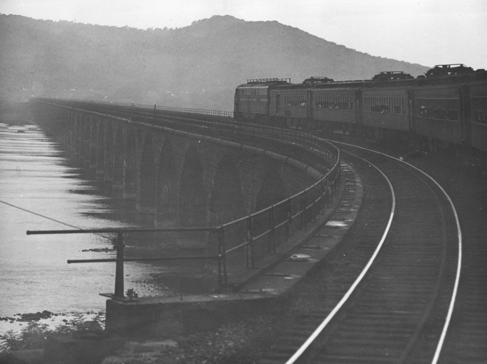Diesel locomotive pulling electric multiple-unit cars across bridge