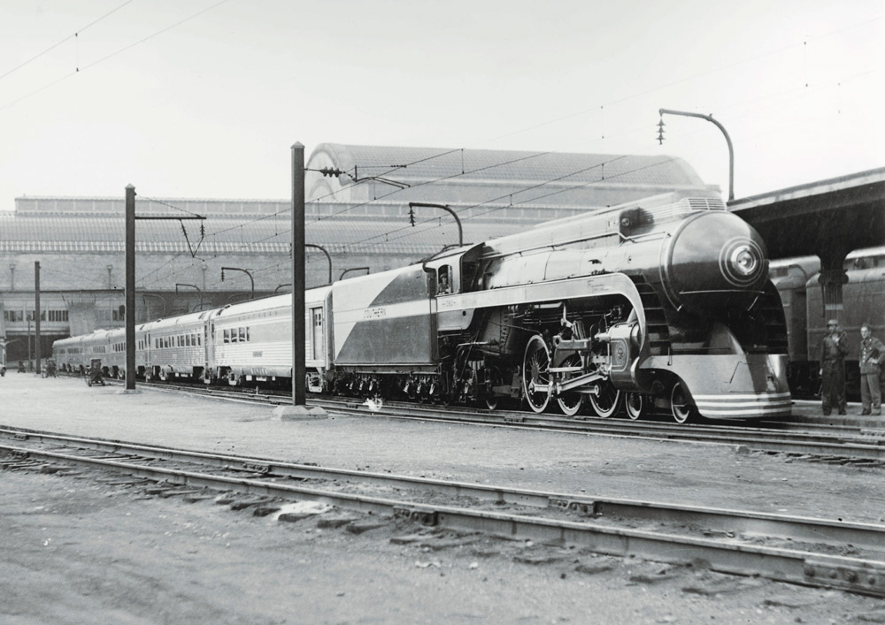 Streamlined steam locomotive with passenger train at station