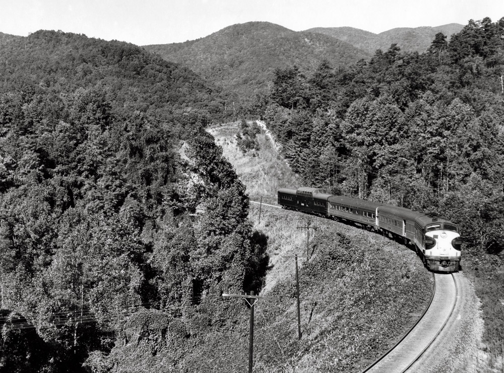 Streamlined diesel locomotive with passenger train in mountains