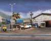 A maintenance crew works on a pair of diesel locomotives outside a shiny corrugated metal maintenance building