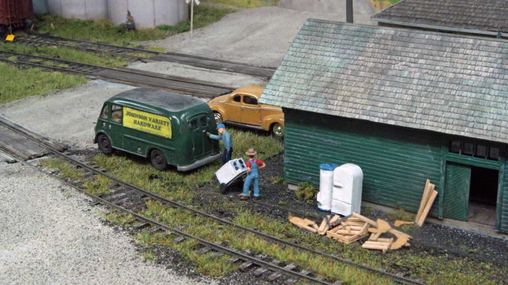 Model figures next to building and vehicles