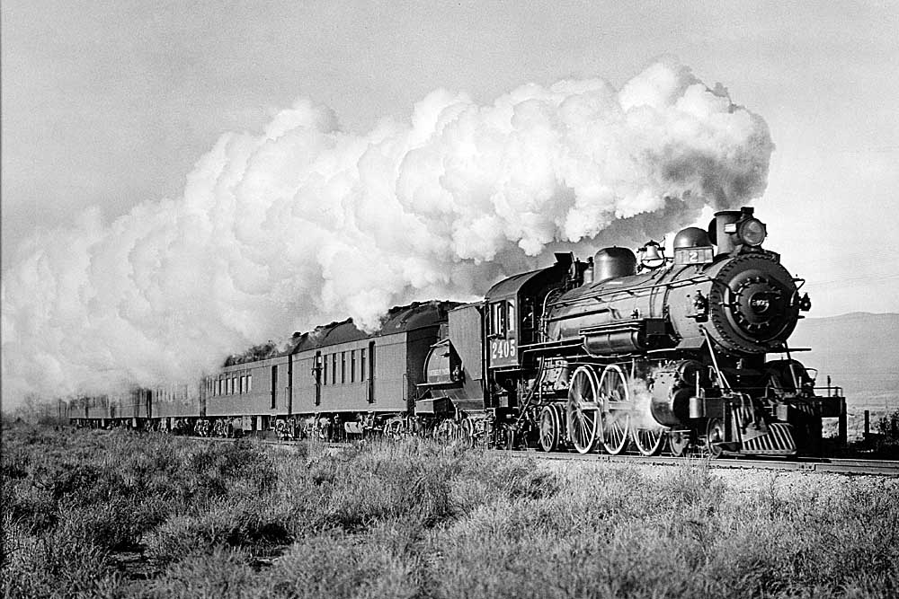Steam locomotive smoking profusely with passenger cars in tow