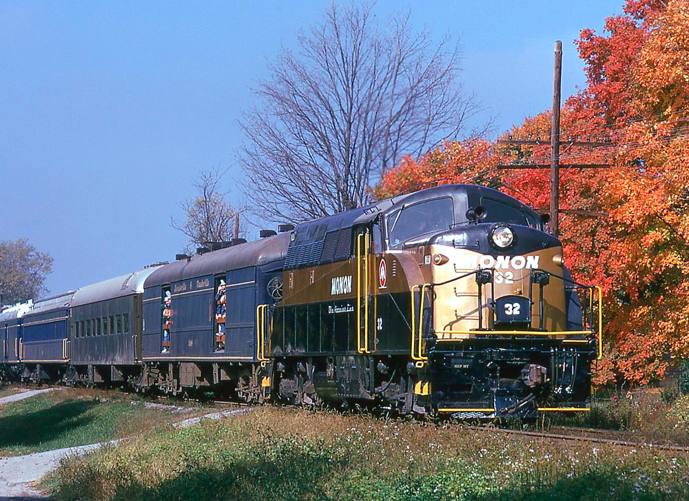 Black and gold diesel locomotive with passenger train