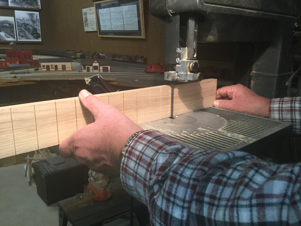 Hands holding a piece of wood at a band saw