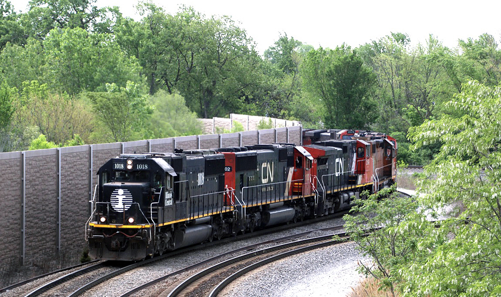 Long string of locomotives led by solid black engine passes through S curve