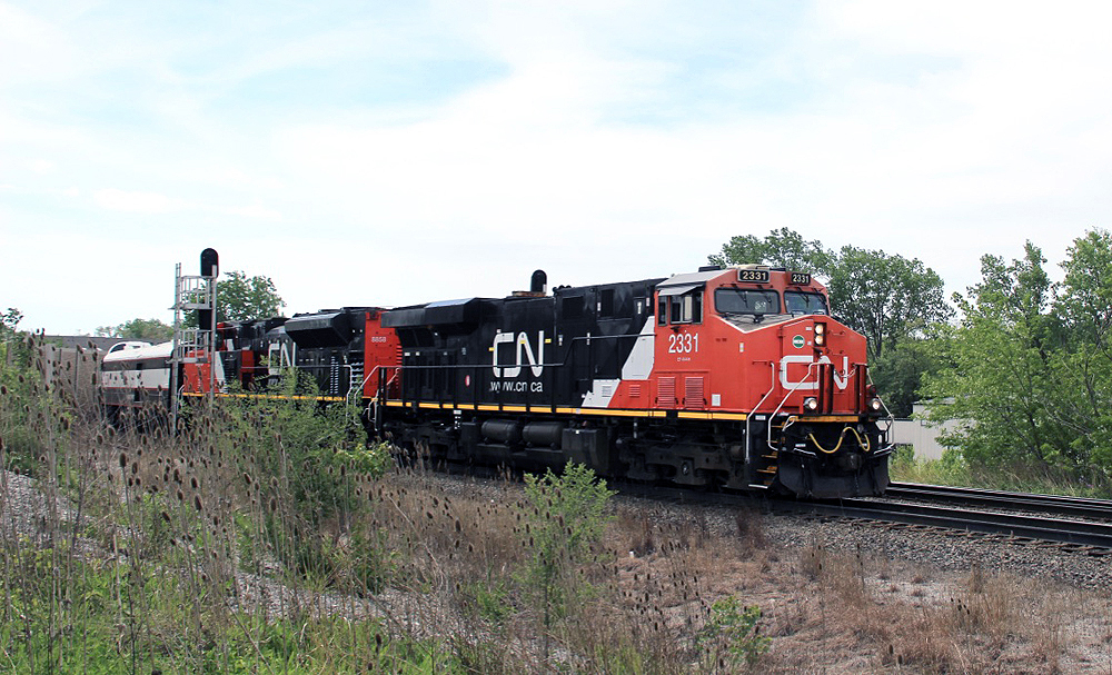 Two red and black locomotives with short passenger train passes signals