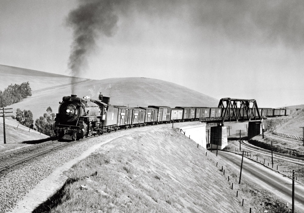Steam powered freight train on a bridge on a curve exhibiting traits of the Western Pacific Railroad