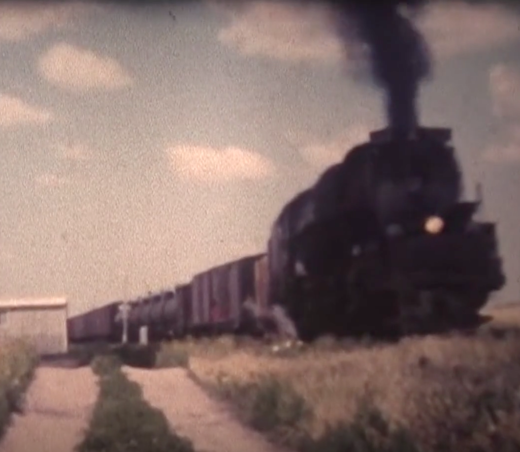 Challenger locomotive hauling a freight train on the plains.