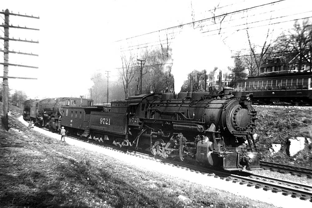 Three steam locomotives led by an 0-8-0 switcher on an incline in a black-and-white image.