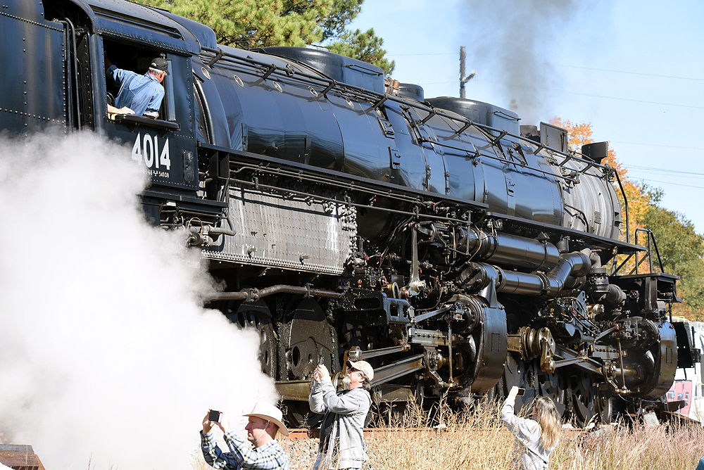Photographers stand in a ditch alongside steam locomotive