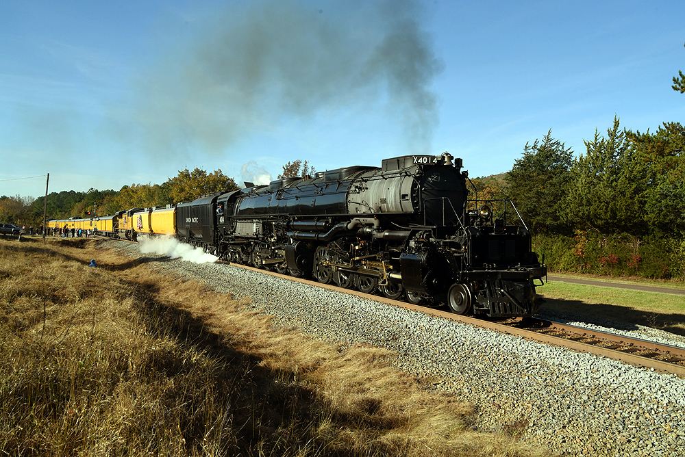 Steam locomotive smoking lightly with yellow passenger train