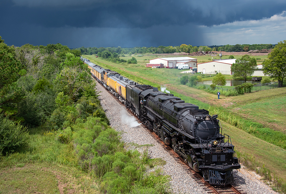 Large black steam locomotive with train against a dark blue sky.