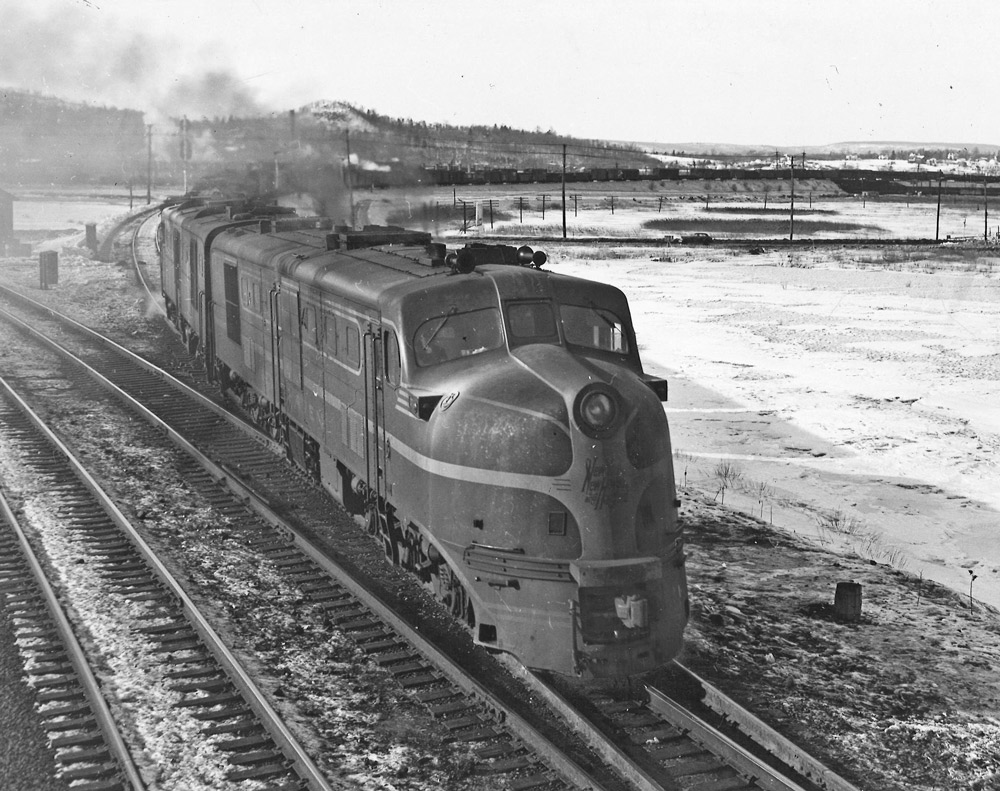 Black-and-white photo of two streamlined diesel locomotives with freight train