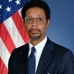 Man in suit in front of U.S. flag