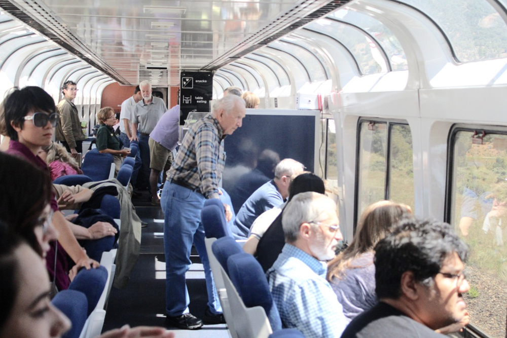 People standing and sitting, facing out windows of passenger car