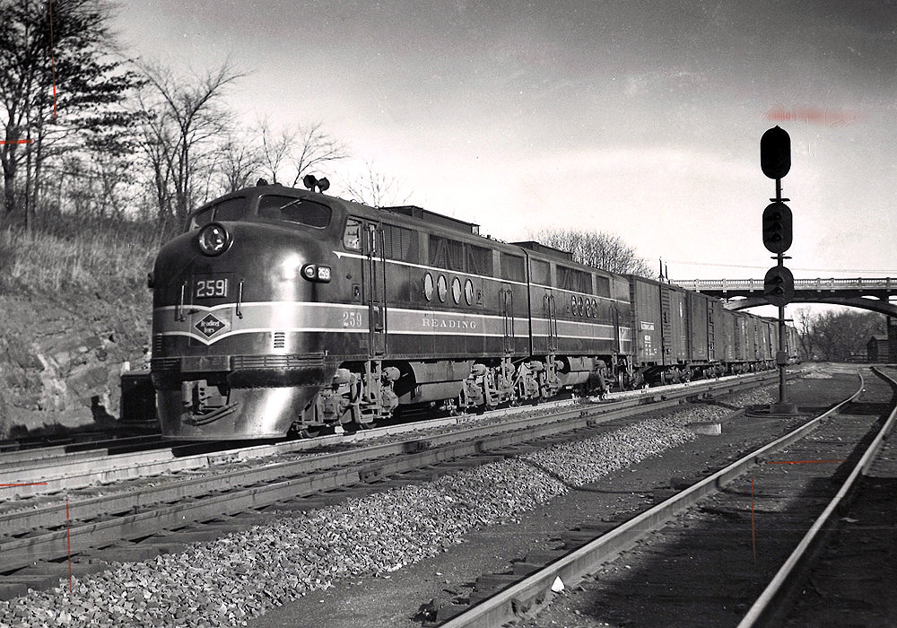 Black-and-white photo of two streamlined diesel locomotives with Reading Company freight train