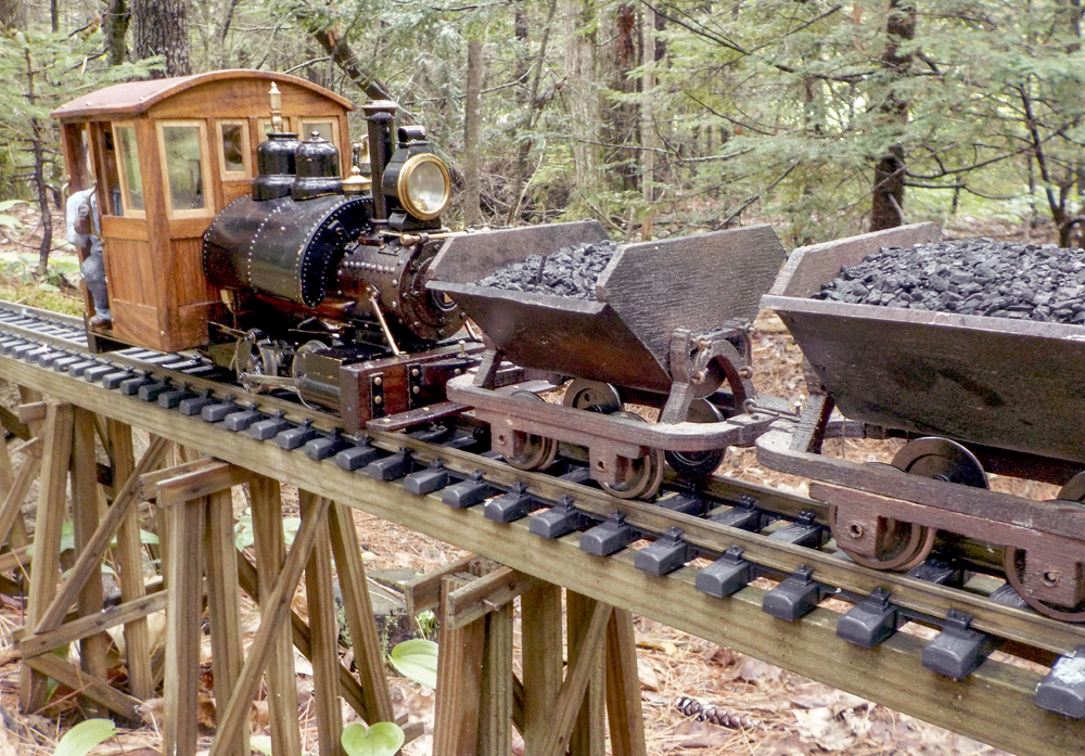 A model locomotive with tipper cars on a garden railway