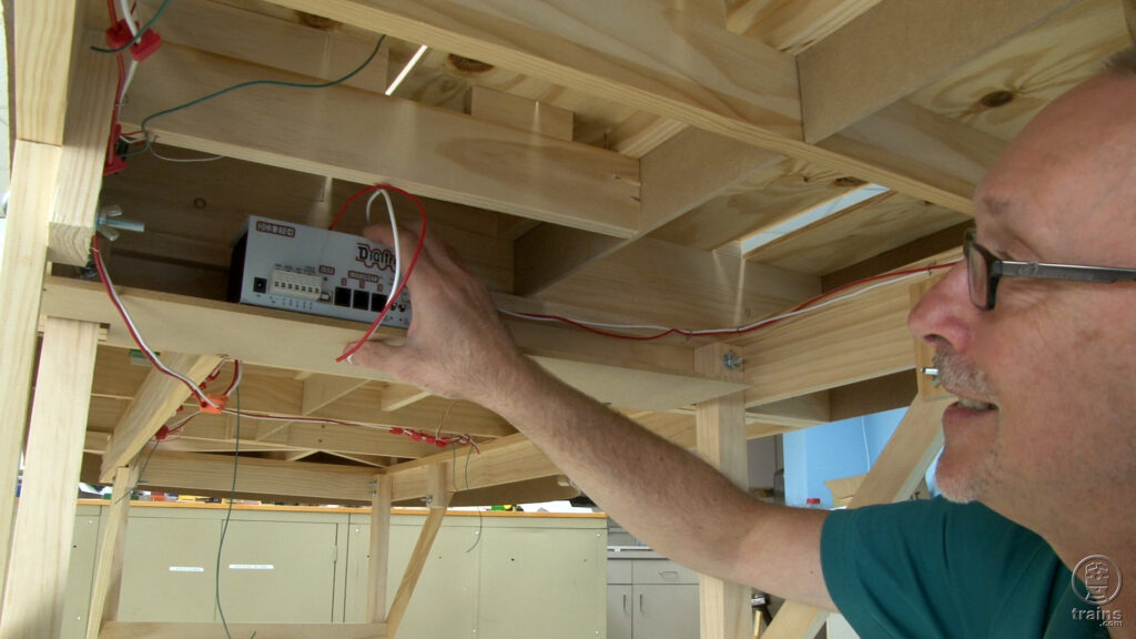 David Popp underneath a model railroad layout installing a DCC system