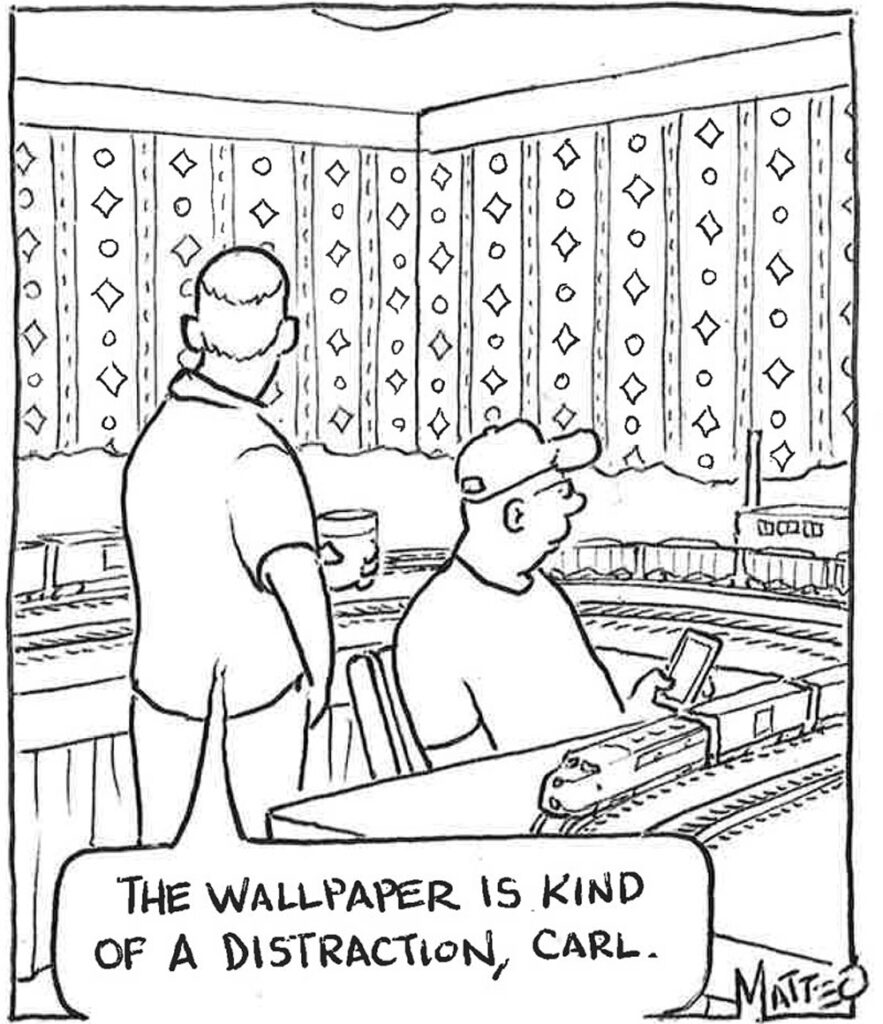 While a man operates his layout, a visitor contemplates the room’s busy patterned wallpaper.