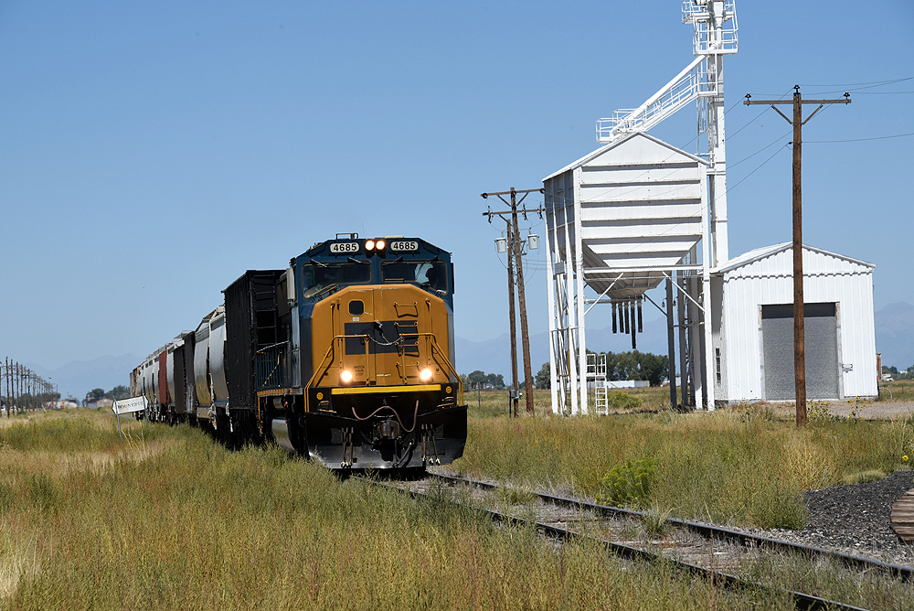 A locomotive hauls a freight train in a flat landscape.