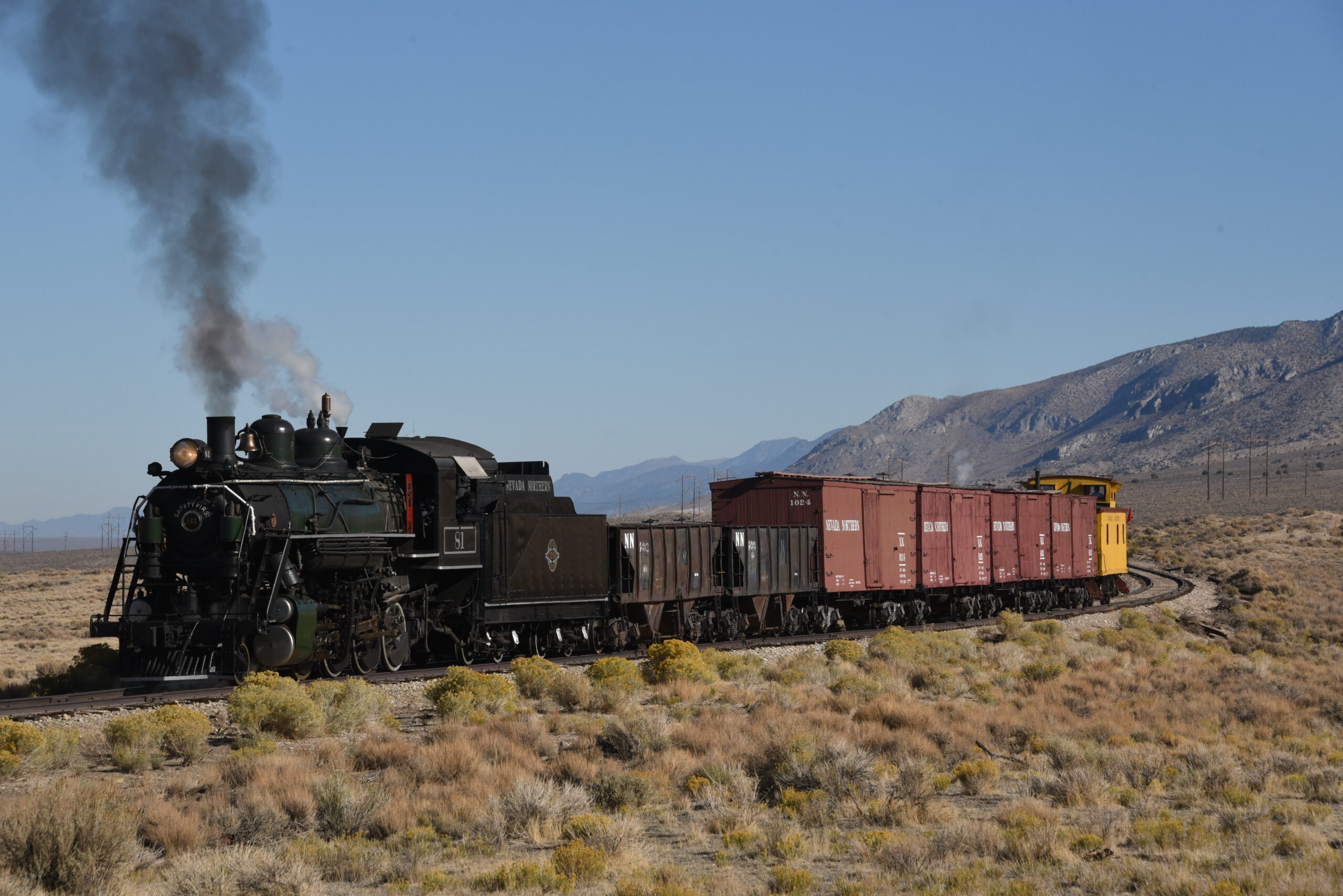 Steam train runs with freight cars in the desert