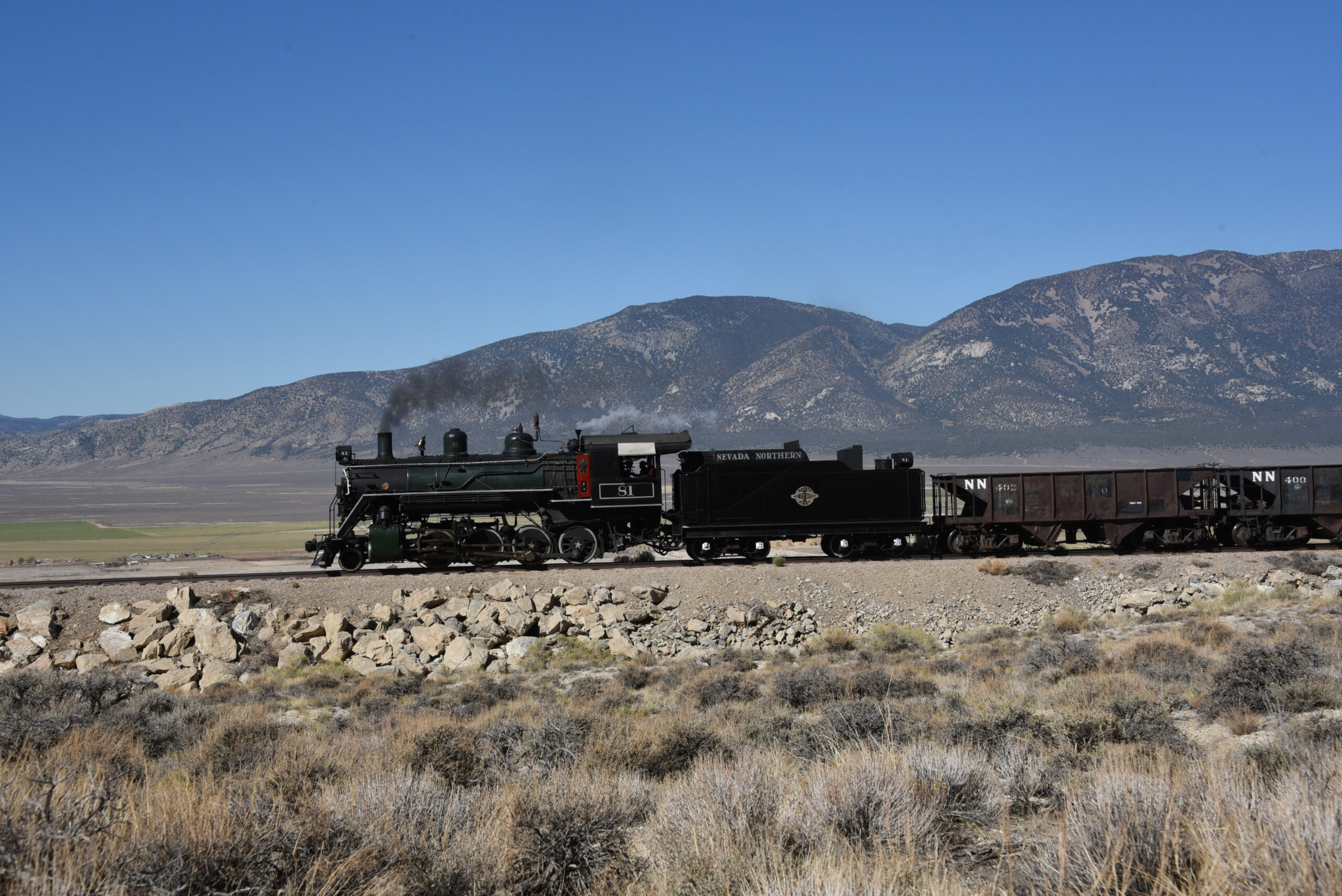 Steam train on hillside overlooking desert valley below