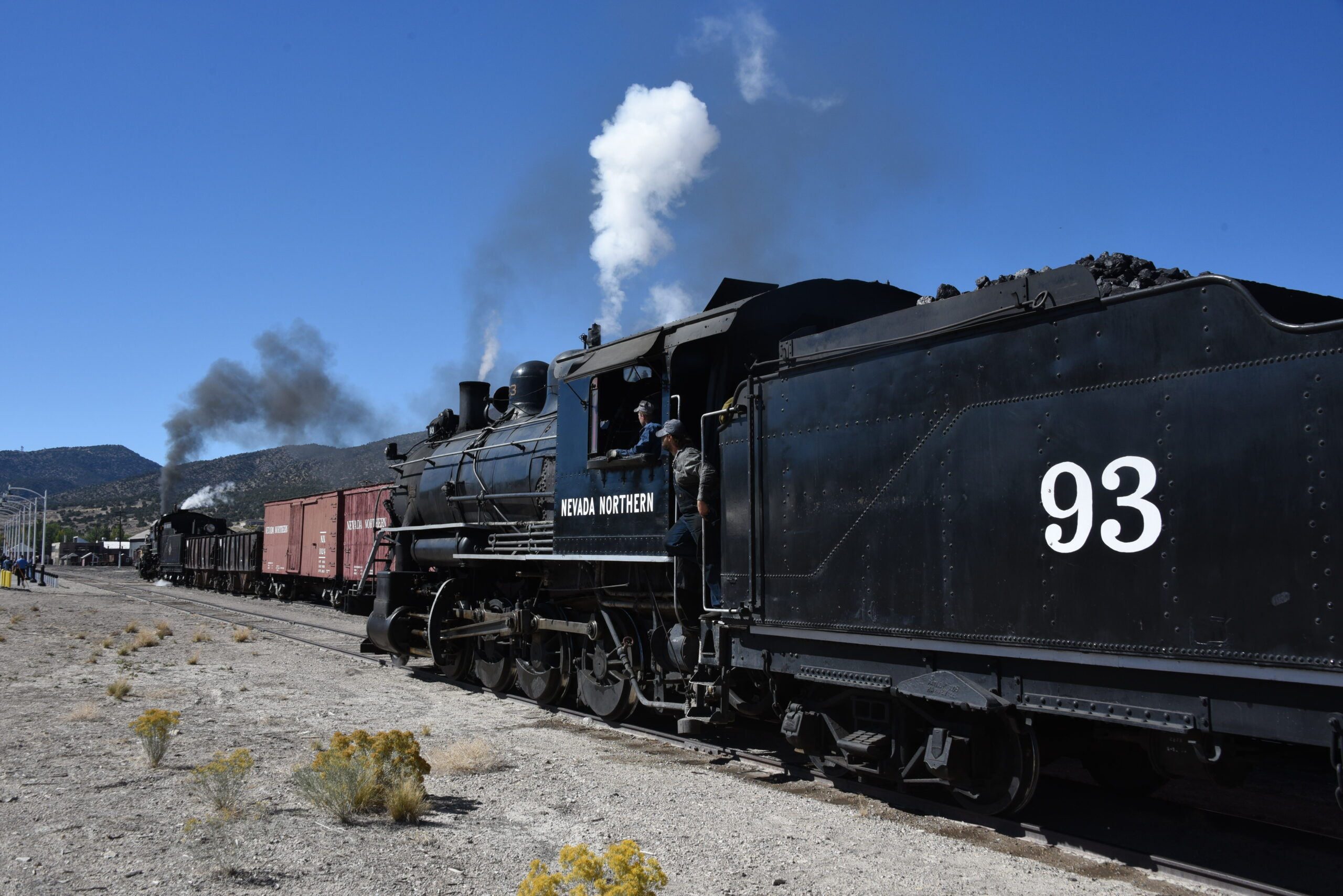 two steam locomotives side by side in railroad yard
