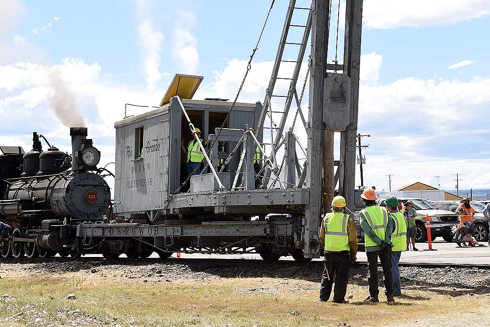 Operating railroad pile driver with crews looking on.