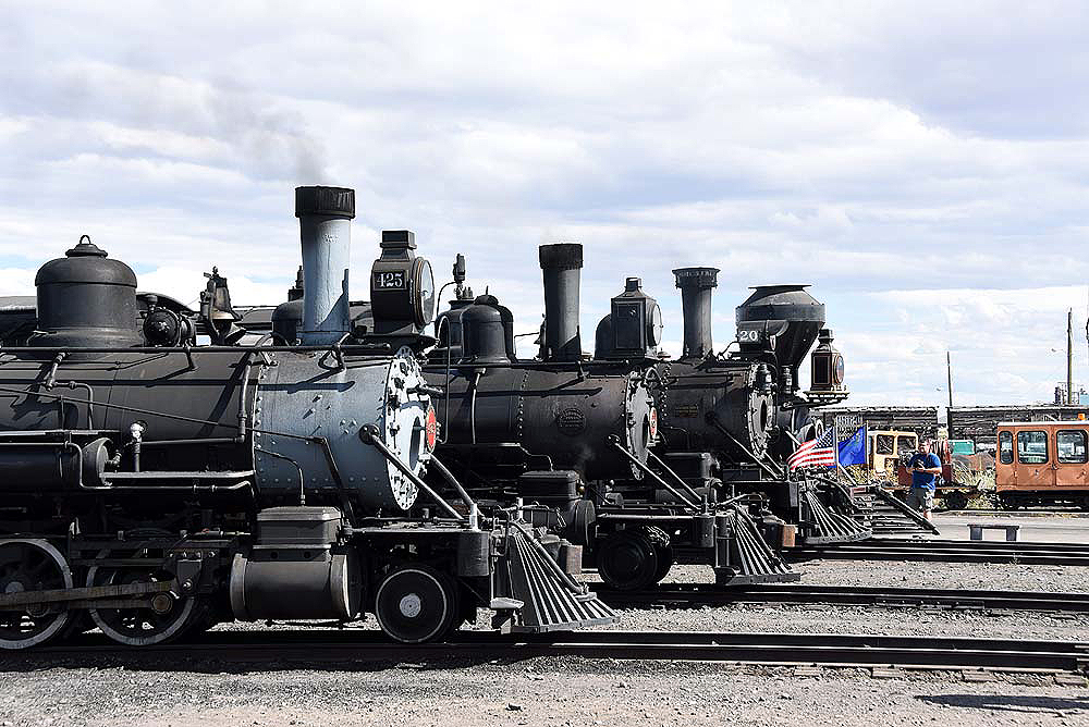 Four steam locomotives line for display in a rail yard.