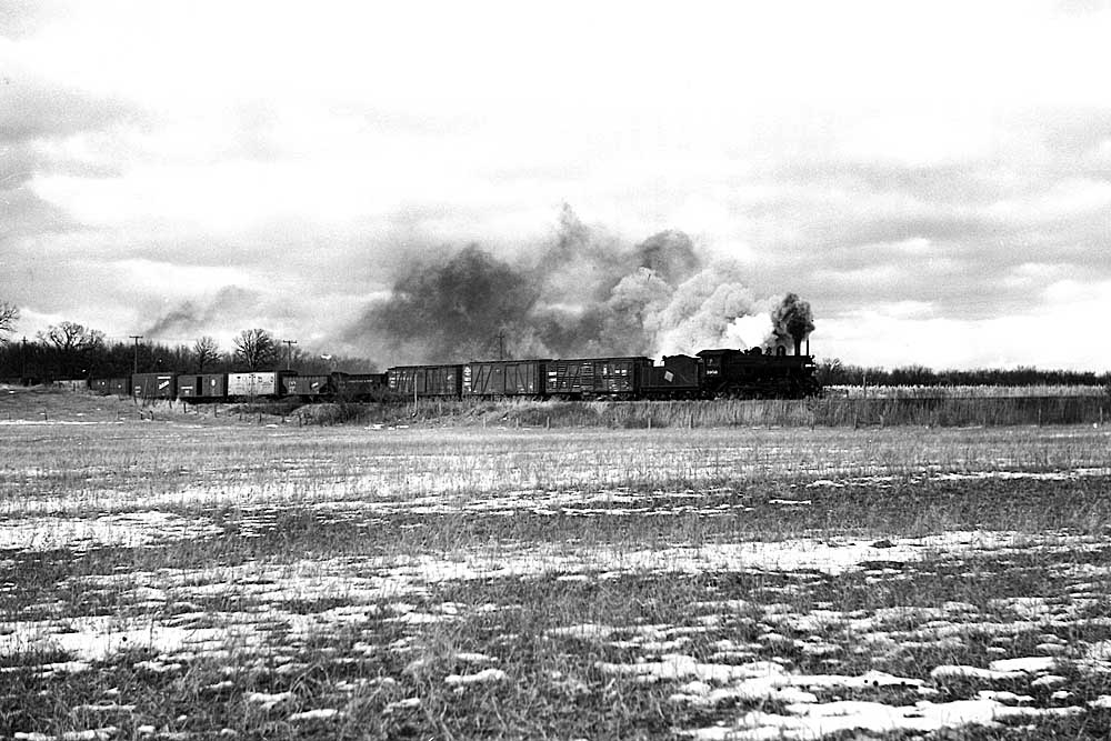 steam locomotive pulls short train through snow-covered fields