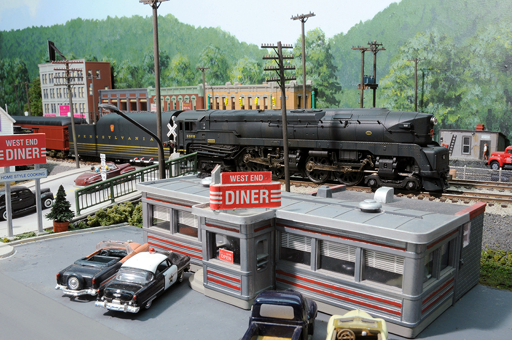 A train passes behind a busy vintage diner