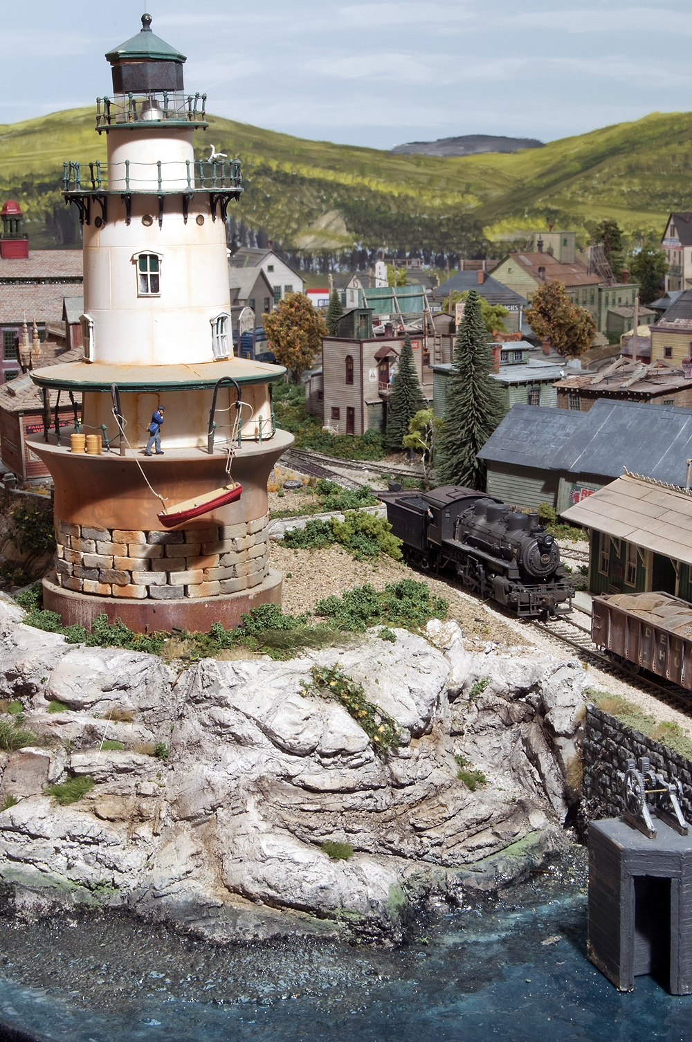 Lighthouse along a water front with train going over a bridge