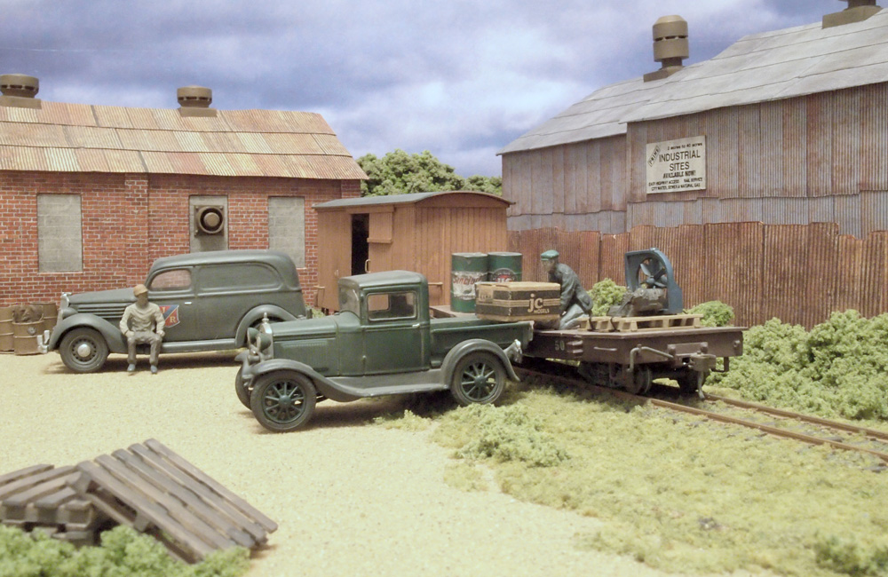 A worker moves a large box from a flatcar on a team track into a pickup truck’s bed