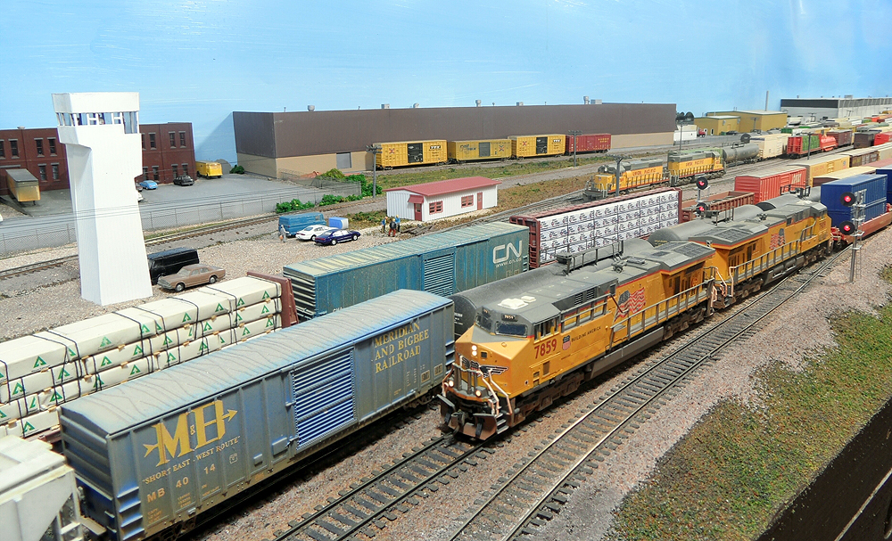 Freight trains in a yard with a white windowed tower in the background.