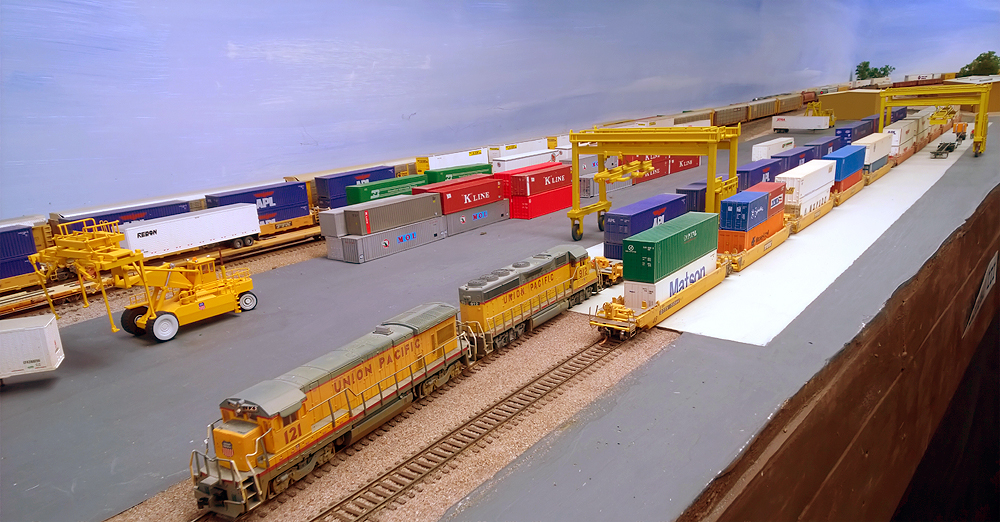 Yellow Union Pacific locomotives at the end of a freight train in a container terminal.