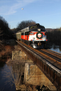 White and red locomotive with wreath on the front crosses steel bridge