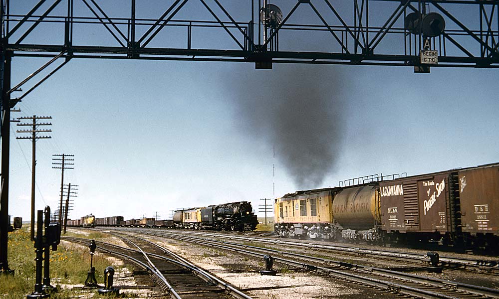 Steam and gas turbine locomotives lead meeting trains under signal bridge